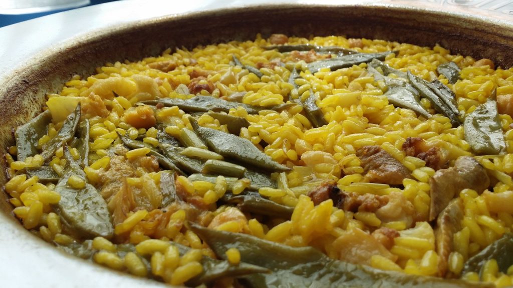 Imagen de una paella típica de valencia junto a todos sus ingredientes